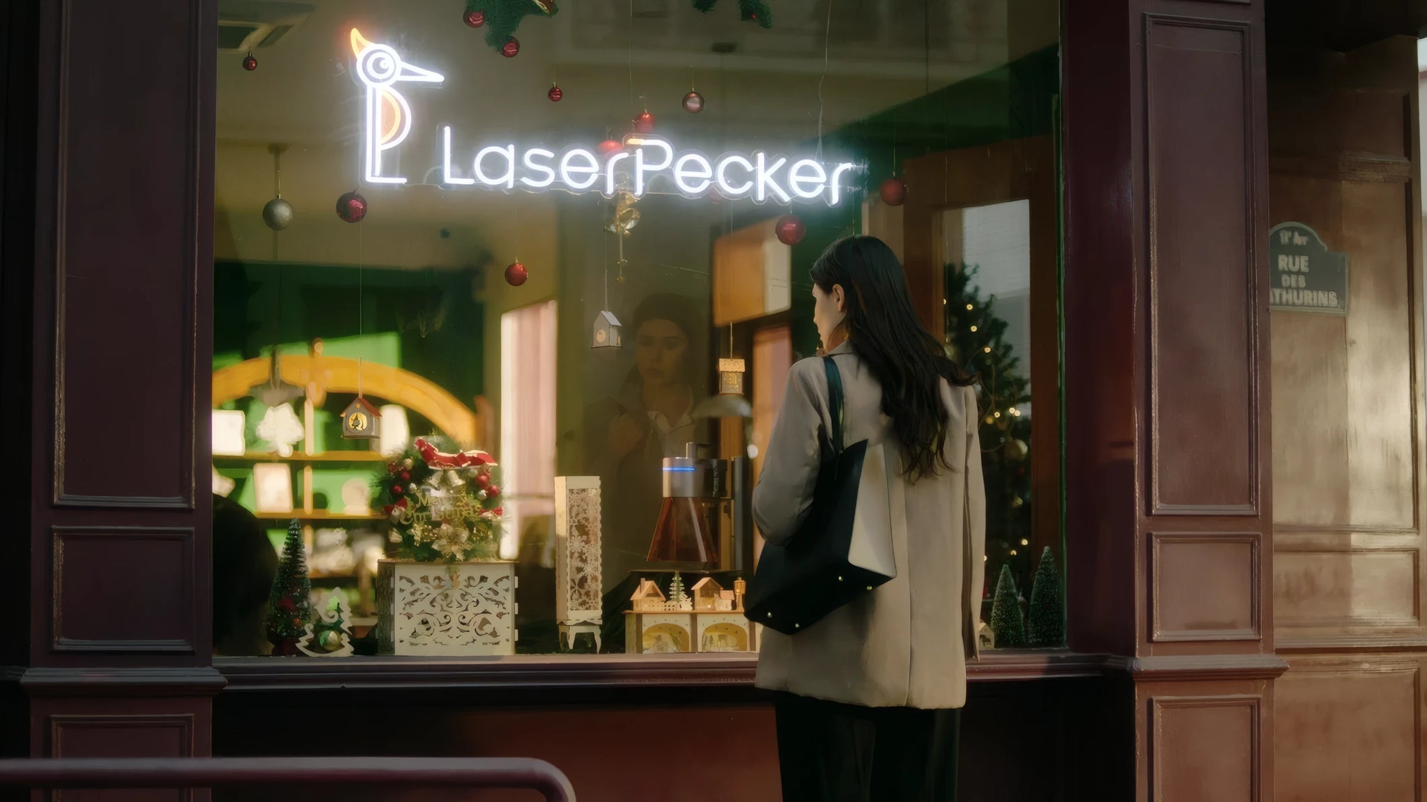レーザーペッカーの店頭ウィンドウの外に立ち、店内に陳列されたパーソナライズ彫刻製品に心を奪われている女性